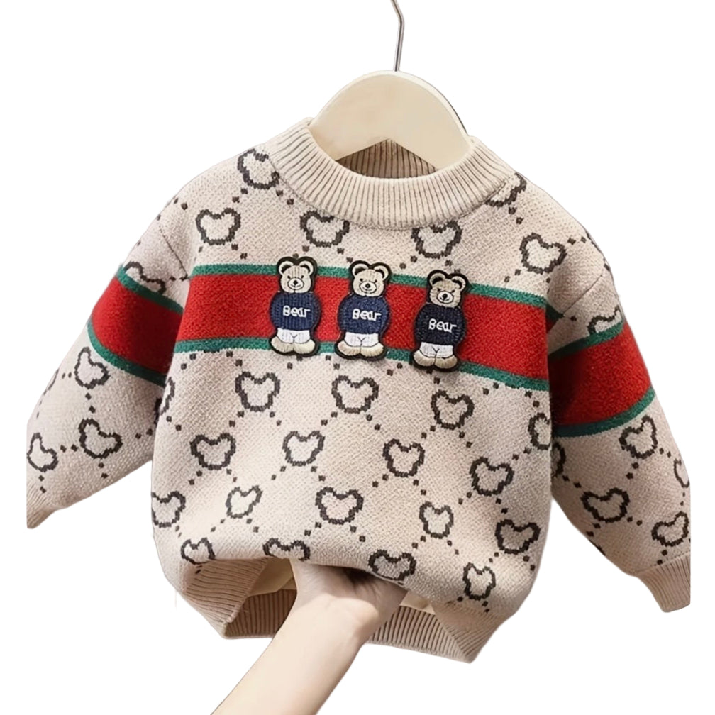 Children's sweater with bear design and red and green stripes on a hanger against a gray curtain background.